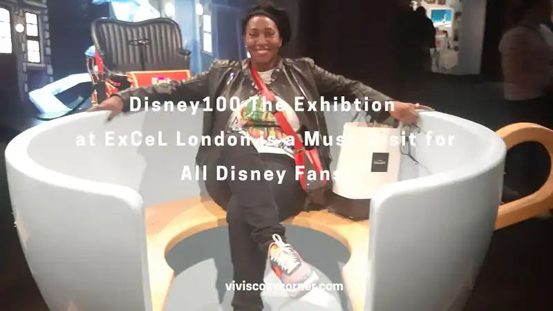 Person sitting inside a giant white teacup chair at the Disney100: The Exhibition exhibit, ExCeL London, smiling at the camera.